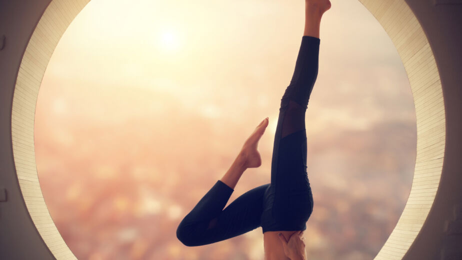 beautiful sporty fit yogi woman practices yoga salamba sarvangasana shoulderstand pose in a window